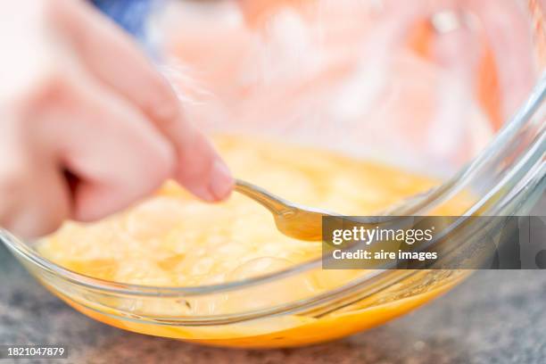 midsection of unrecognizable human hand using fork kitchen utensil beating eggs liquid in bowl - roerei stockfoto's en -beelden