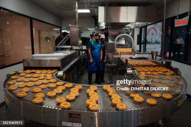 Worker checks Krispy Kreme doughnuts during a press preview at a restaurant in central Paris, on December 4, 2023. The first Krispy Kreme restaurant...