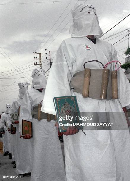 Palestinian members from the radical Jihad movement girded with fake explosives hold copies of the Koran during an anti-Israeli demonstration in the...