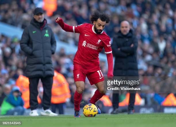 Mohamed Salah of Liverpool is watched by Liverpool manager Jurgen Klopp and Manchester City manager Pep Guardiola during the Premier League match...