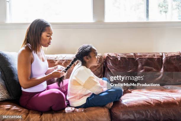 mother brushing her daughters hair on couch at home - weaving stock pictures, royalty-free photos & images