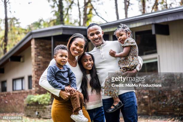 portrait of family with young children in front of suburban home - mature man smiling 40 44 years blond hair stock pictures, royalty-free photos & images