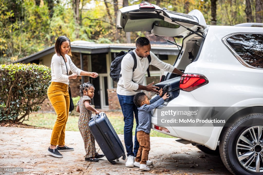 Family loading suitcases in car for family vacation
