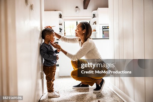 Mother measuring son's height on wall in kitchen Mother measuring son's height on wall in kitchen