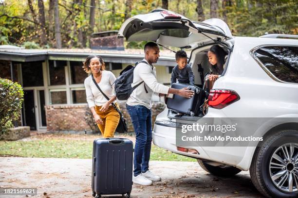 family loading suitcases in car for family vacation - trip photos et images de collection