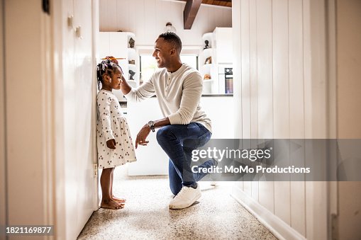 Father measuring daughter's height on wall in kitchen Father measuring daughter's height on wall in kitchen