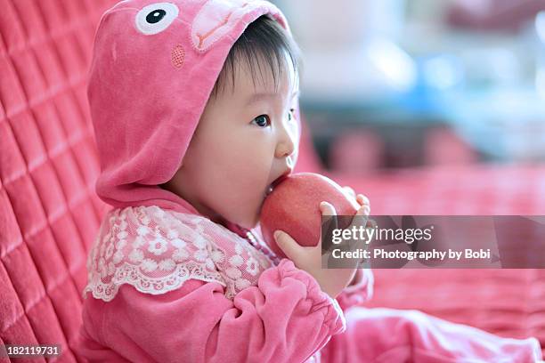 little girl eating an apple on the sofa - orient stock-fotos und bilder