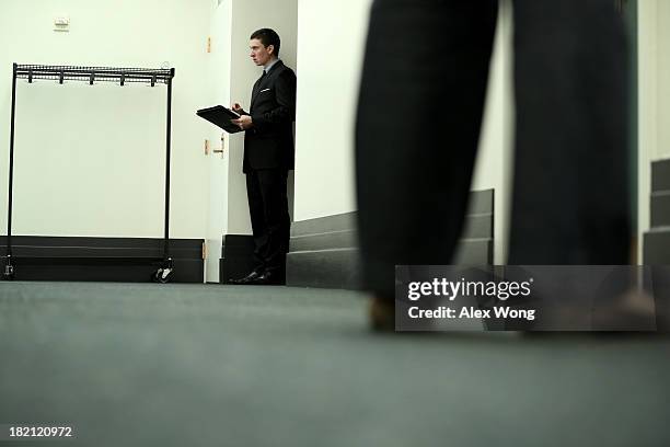 Congressional aide waits at the entrance during a House Republican Conference meeting September 28, 2013 on Capitol Hill in Washington, DC. The House...