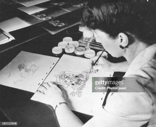 At Walt Disney Studios, an unidentified animator, an unidentified colorist in the Ink and Paint Division works on a drawing of Donald Duck,...