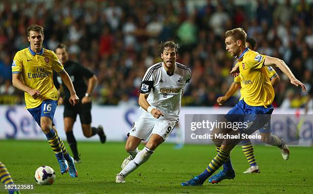 Michu of Swansea City passes as Per Mertesacker of Arsenal closes in during the Barclays Premier League match between Swansea City and Arsenal at the...