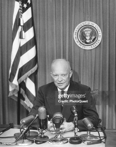 American politician US President Dwight Eisenhower sits behind a bank of microphones as he addresses the press, October 22, 1953.