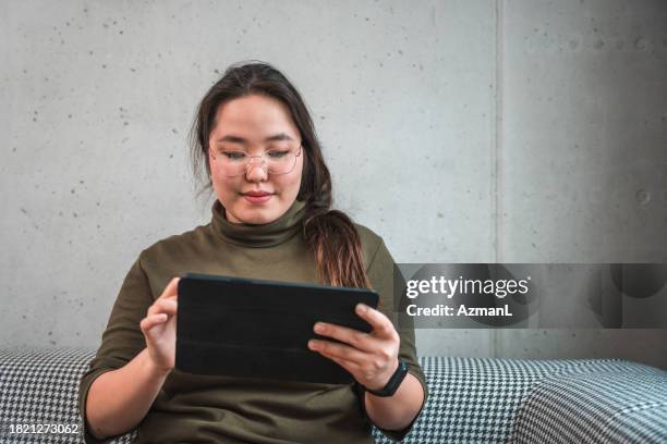 serious asian woman with glasses  using tablet and focusing - crosswords stock pictures, royalty-free photos & images