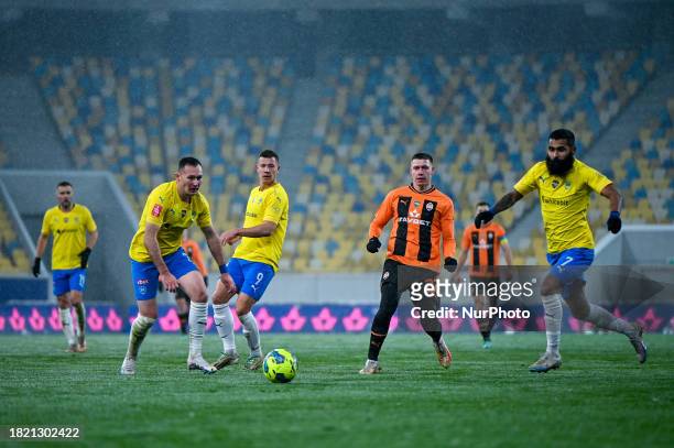 Players from FC Shakhtar Donetsk, wearing orange and black kits, and FC Metalist 1925 Kharkiv, in yellow and blue kits, are competing during the 16th...