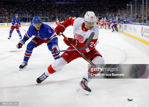 Braden Schneider of the New York Rangers checks Klim Kostin of the Detroit Red Wings during the first period at Madison Square Garden on November 29,...