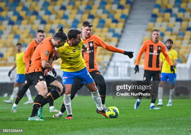 Players from FC Shakhtar Donetsk, wearing orange and black kits, and FC Metalist 1925 Kharkiv, in yellow and blue kits, are competing during the 16th...