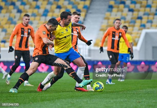 Players from FC Shakhtar Donetsk, wearing orange and black kits, and FC Metalist 1925 Kharkiv, in yellow and blue kits, are competing during the 16th...