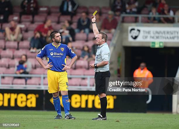 Assistant referee David Rock who replaced injured referee Darren Sheldrake shows a yellow card to Alex Kenyon of Morecambe during the Sky Bet League...