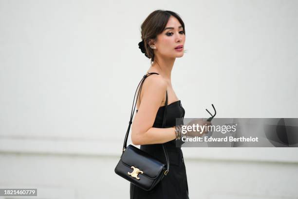 Heart Evangelista wears sunglasses, a hair clamp / clip, earrings, a black off-shoulder / low-neck / corset top from COS, a Celine black leather bag...
