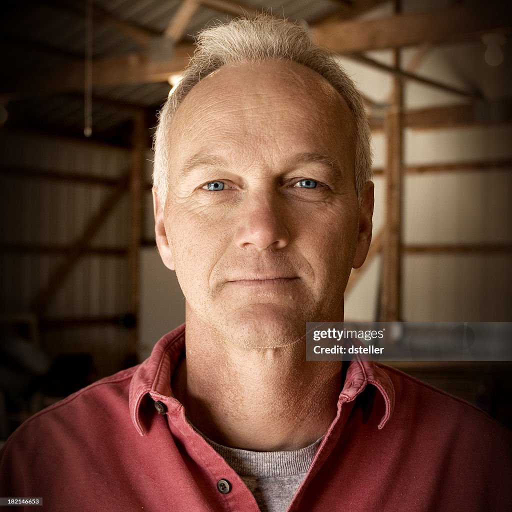 Man facing camera with interior of barn as the background