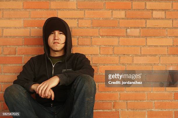 teenage boy dressed in black crouched down on brick wall  - hingst bildbanksfoton och bilder