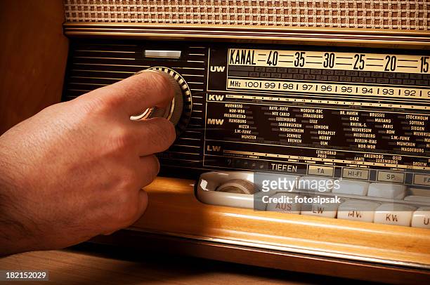 vintage short wave radio with person's hand on the tuner - radio stockfoto's en -beelden