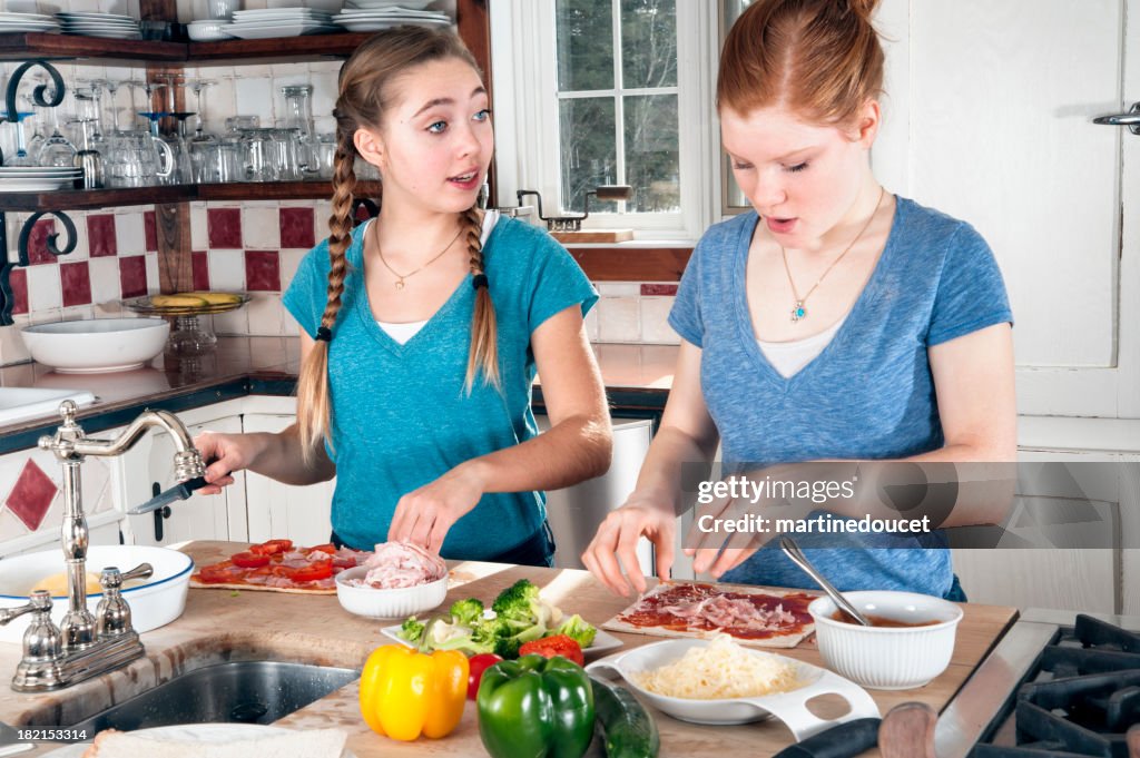 Two teenagers making pizza in modern kitchen