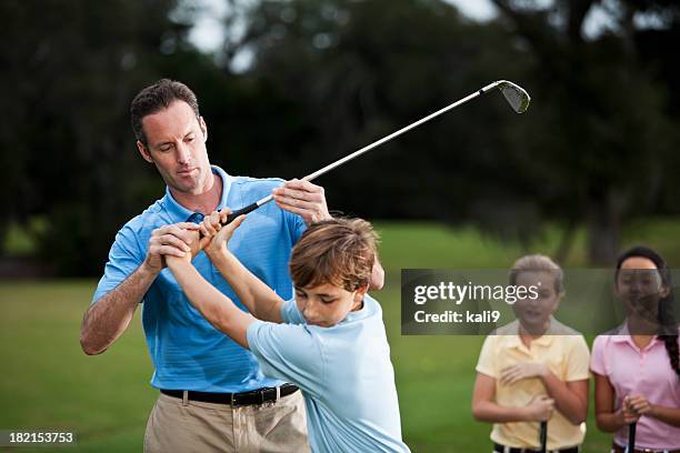 golf instructor adjusting boy's grip - golf lessons stock pictures, royalty-free photos & images