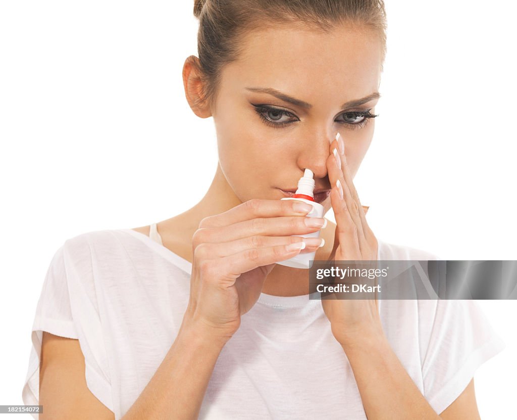 Woman with cold using nasal spray