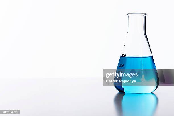 blue liquid in half-filled laboratory flask against white background - acrylic glass stock pictures, royalty-free photos & images