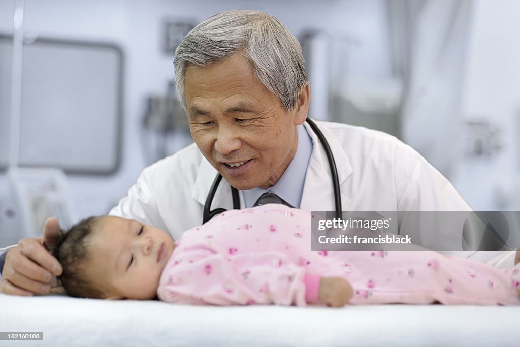 Hombre asiático médico examinar bebé niña.