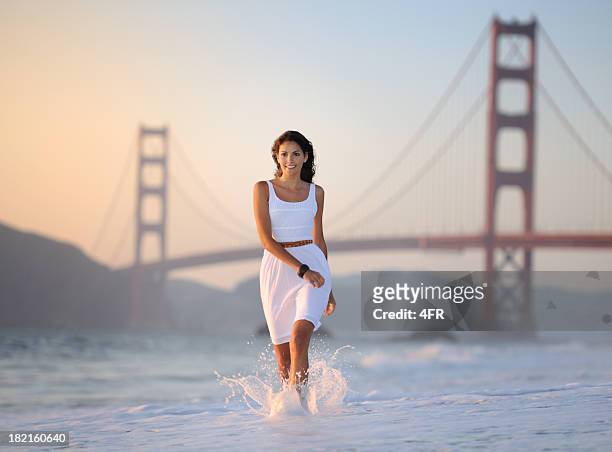 woman running playful through the surf, golden gate bridge (xxxl) - baker beach stock pictures, royalty-free photos & images
