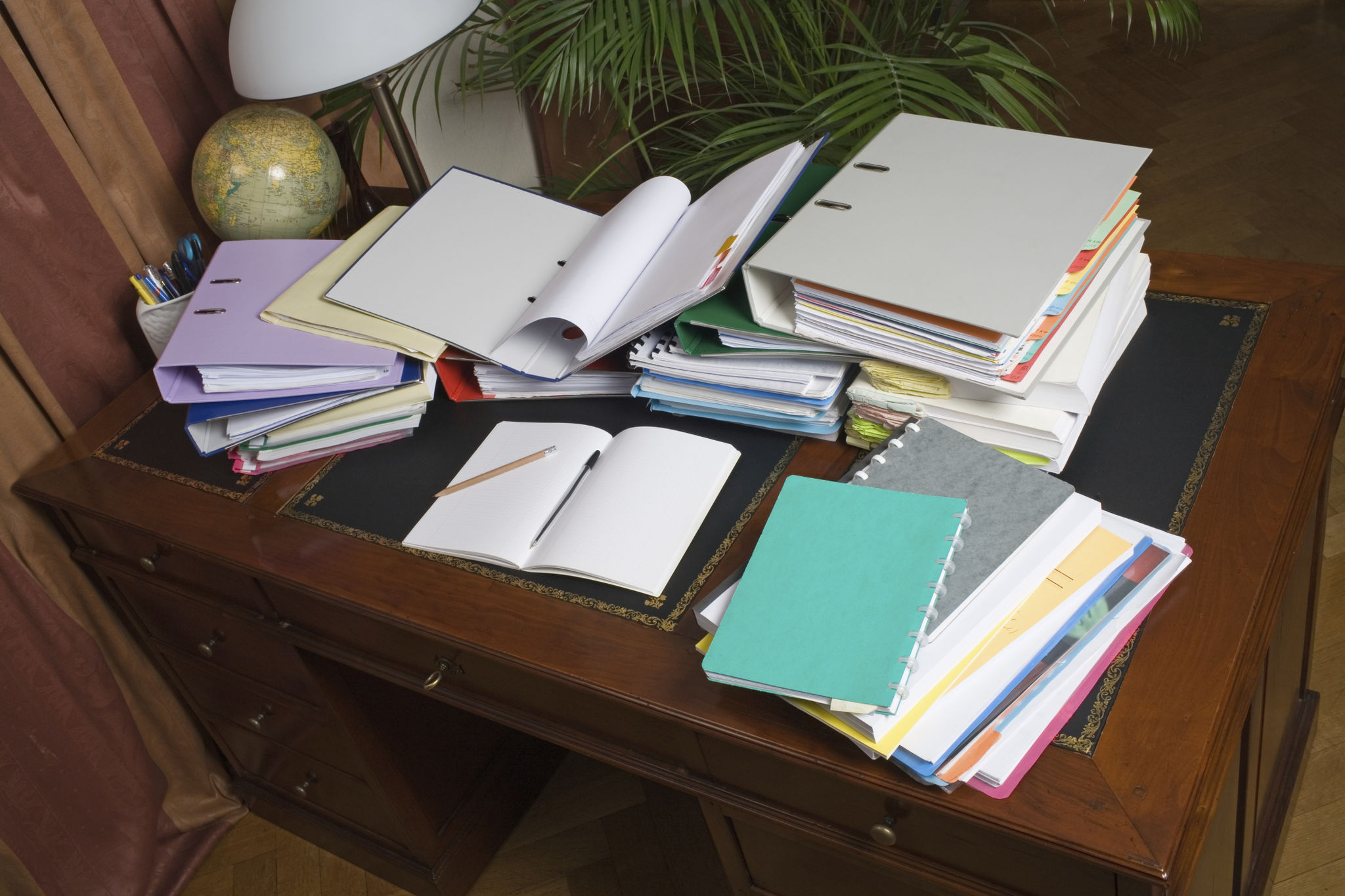 Desk, cluttered with binders and paper Desk, cluttered with binders and paper