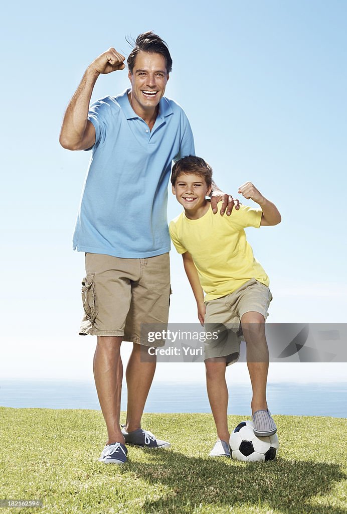 Excited father and son standing outside with a football