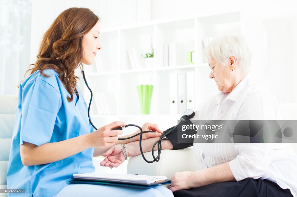 Médico haciendo presión arterial revise a Senior mujer.