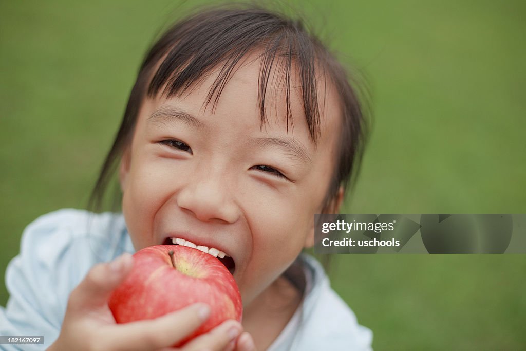 Mignonne petite fille asiatique mangeant une pomme