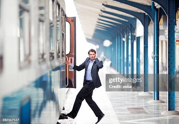 businessman boarding onto a train while talking on the telephone - stappen stockfoto's en -beelden