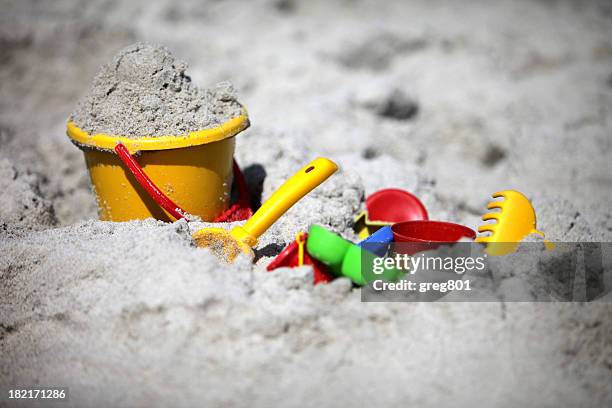 a close-up of a bucket and shovel in the sand of a beach - zandbak stockfoto's en -beelden