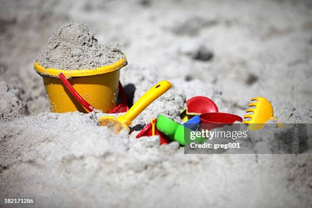 a close-up of a bucket and shovel in the sand of a beach - beach bucket stock pictures, royalty-free photos & images