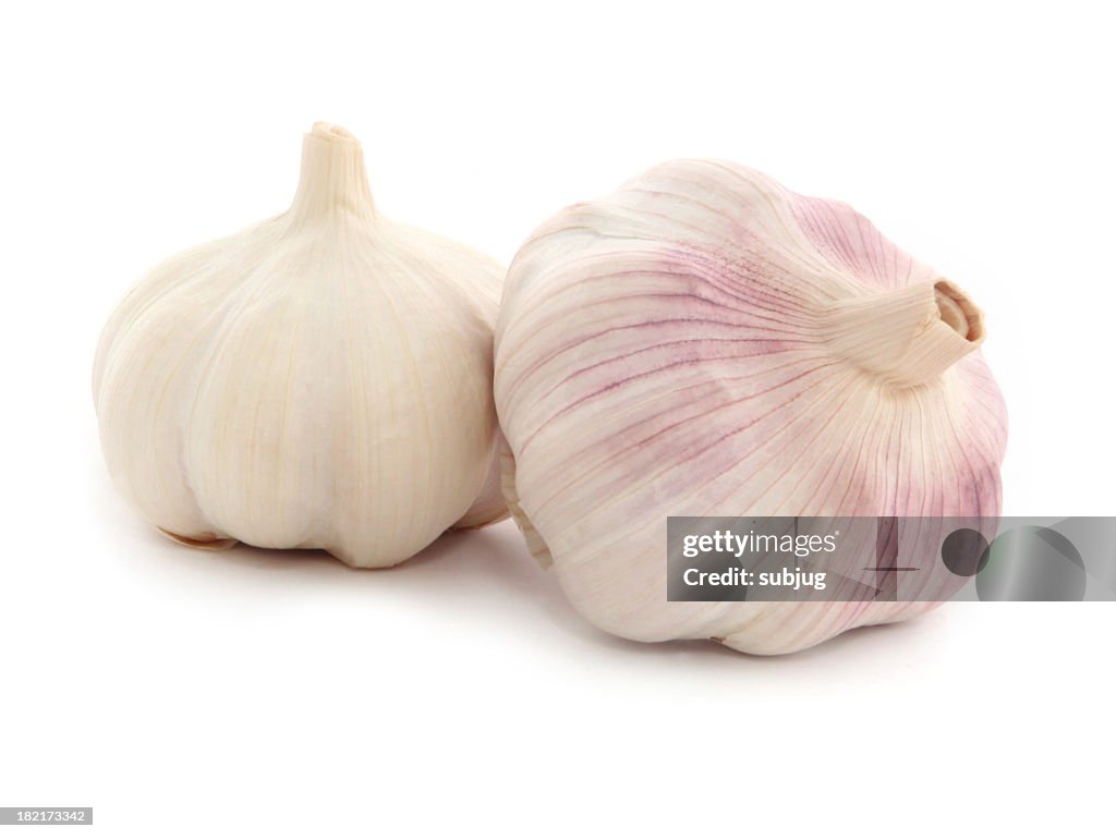 Two whole garlic bulbs one tinted purple on white background