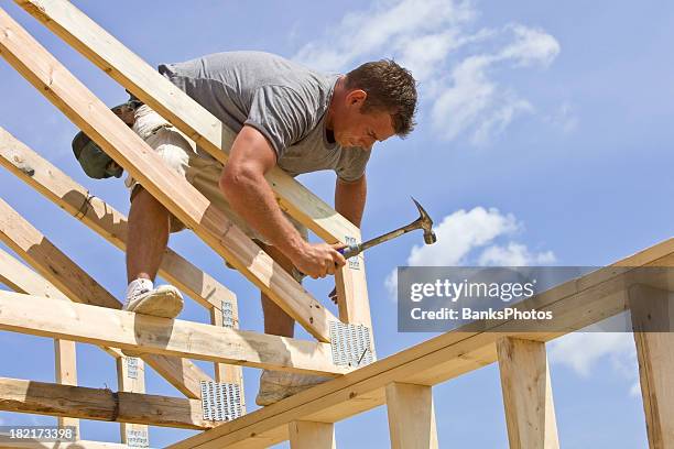 builder hammering roof truss nail against blue sky - roof truss stock pictures, royalty-free photos & images