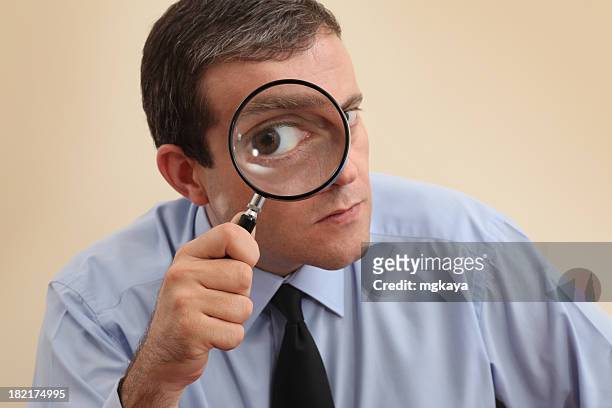businessman looking at camera through a magnifying glass - magnifying glass bildbanksfoton och bilder