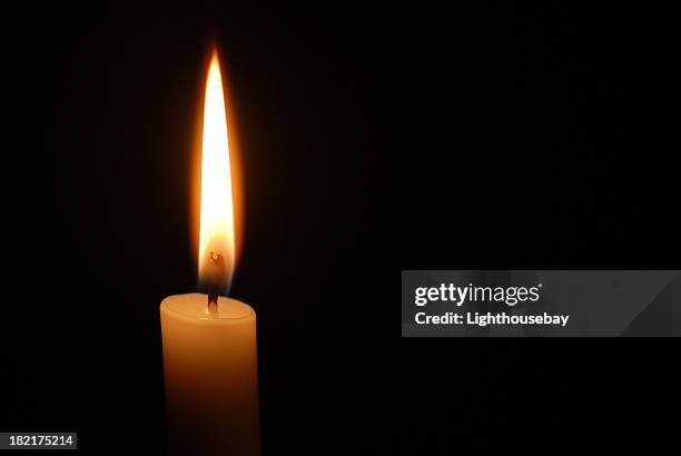 single candle flame on horizontal black background - candle flame stockfoto's en -beelden