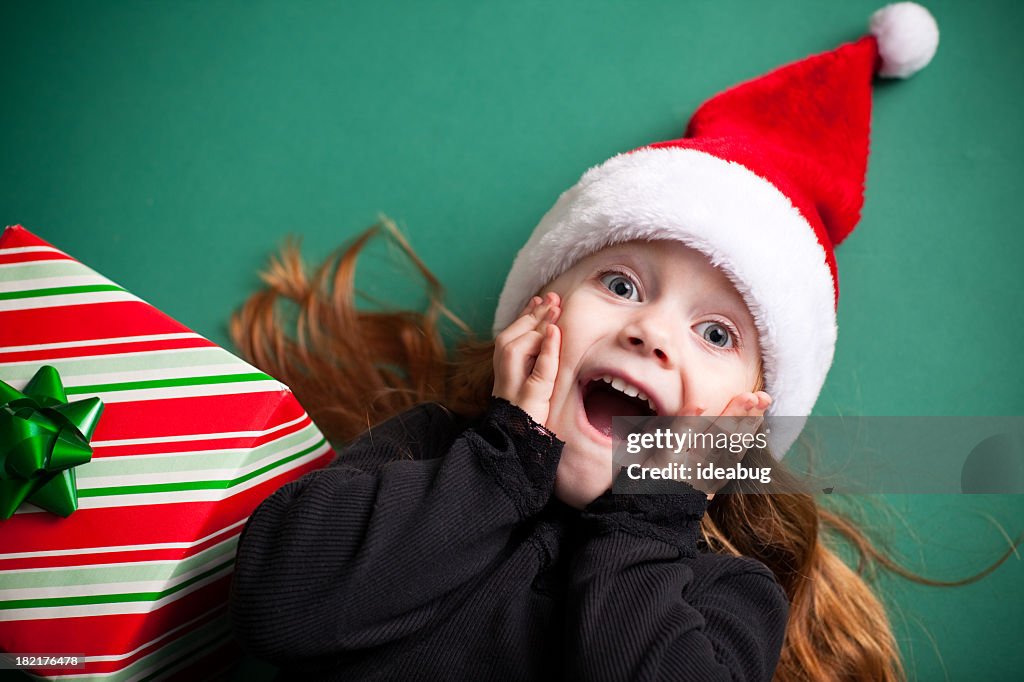 Excité fille portant Chapeau de Père Noël avec cadeau de Noël