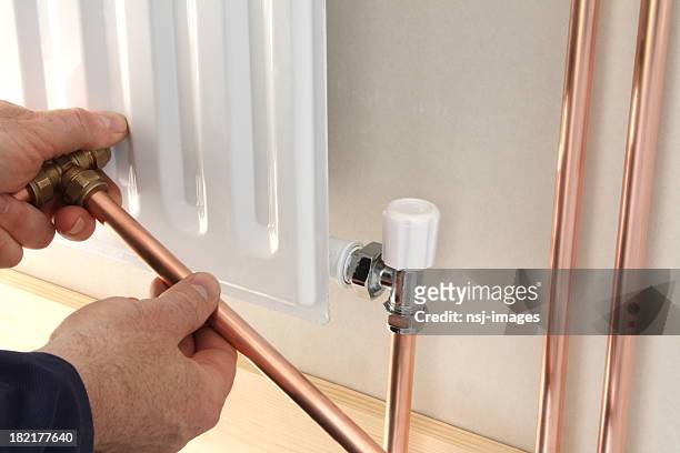 a plumber installing a new radiator - installation stockfoto's en -beelden