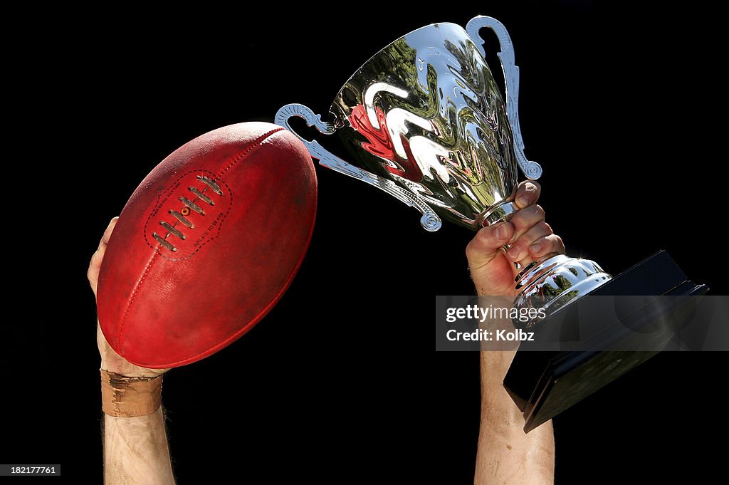 AFL Ball and Trophy Held Aloft