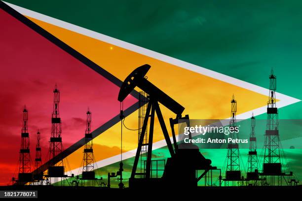 oil rigs on the background of guyana flag - guyana stock-fotos und bilder