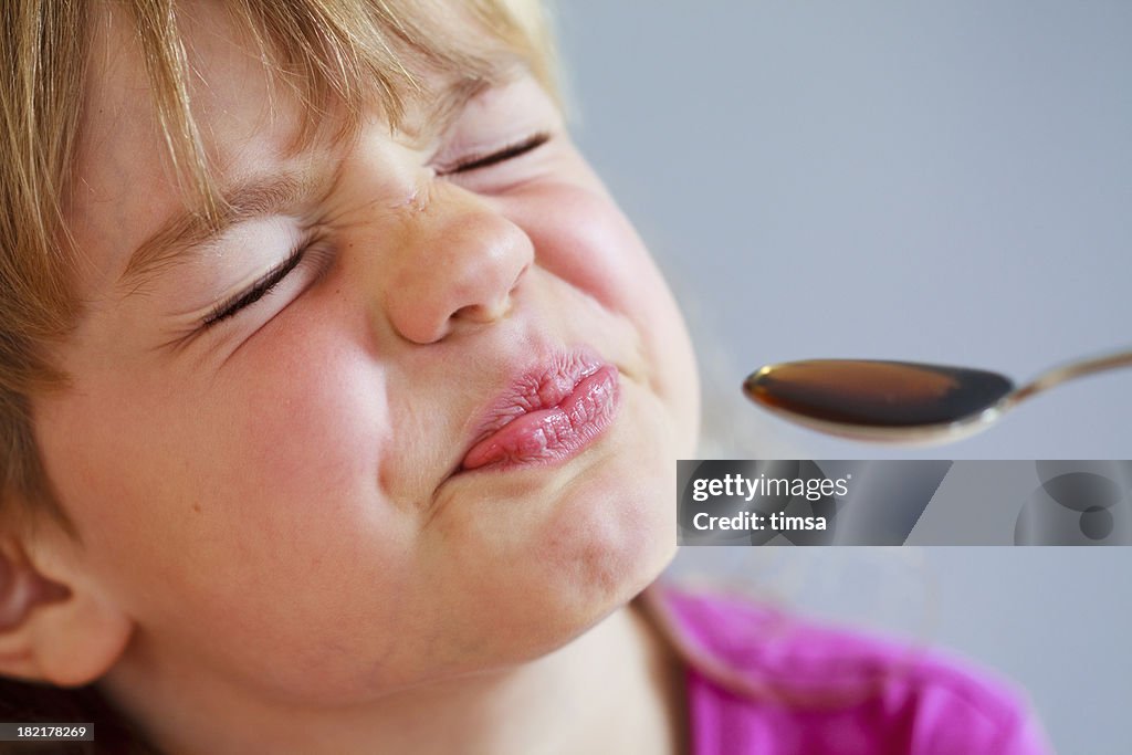 Bitter medicine and girl grimaces