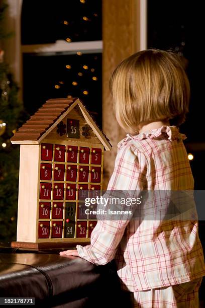 a little girl in pajamas playing with an advent calendar - christmas calendar stockfoto's en -beelden
