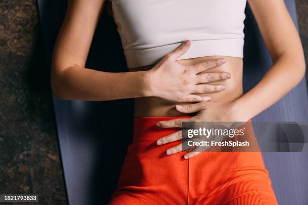 felicidad tranquila: mujer anónima acostada en esterilla de yoga, manos en el vientre en relajación - abdomen fotografías e imágenes de stock
