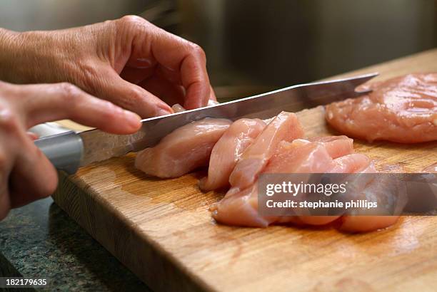 woman cutting raw chicken on a wooden cutting board - salmonella bacterium stock pictures, royalty-free photos & images